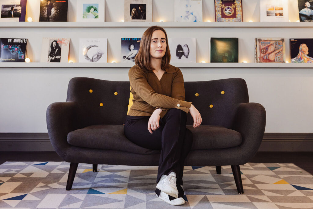 Musician sits on couch surrounded by records