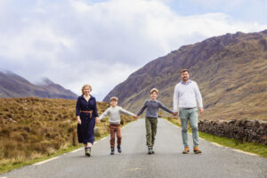 A family walk hand in hand along a road in Doolough Valley, CO Mayo